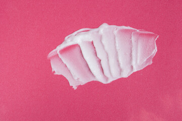 Smear of white face cream on pink background. Cosmetic product texture