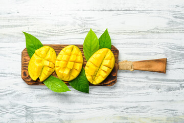 Slices of sweet mango on a white wooden background. Rustic style. Top view. Tropical fruits.