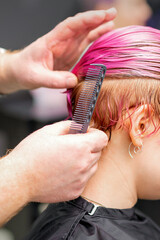 Styling female hair. Male hairdresser makes hairstyle for a young woman in a beauty salon