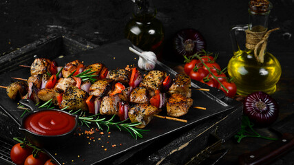 Traditional Kebab. Juicy chicken kebab with vegetables on a black stone plate. Barbecue. Top view....