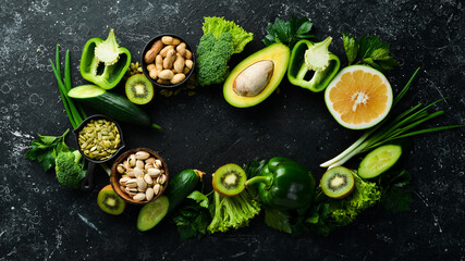 Green vegetables, fruits and nuts: avocado, broccoli, pistachios, parsley, celery, cucumber and kiwi. Top view. Rustic style.