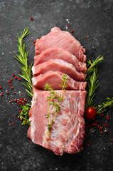 Raw pork fillet with spices on a black stone background. Meat. Top view. Rustic style.
