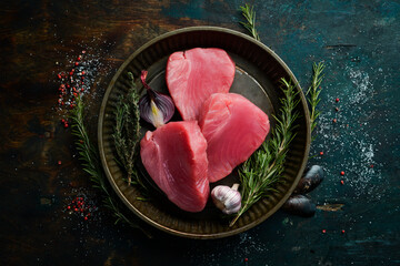 Raw tuna steak with rosemary. On a dark background. Flat lay.