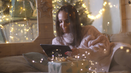 Young pretty woman happy smile on digital tablet at night cozy home enjoy festive winter season. 3840x2160