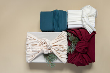Trendy zero waste gift wrapping. Four Christmas presents in fabric on beige background. Sustainable...