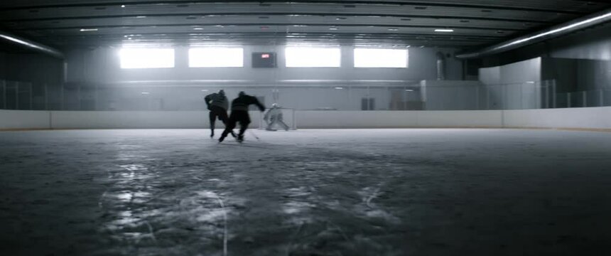 WIDE HANDHELD Determined professional ice hockey players practicing at the indoor rink. Shot with 2x anamorphic lens