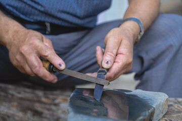 Old mans hands sharpening knives, village life and natural tree texture