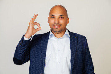 Young african american man smiling positively, making okay hand and fingers sign. Lucky expression. Black man feeling successful and contented, smiling making a sign ok with his hand