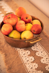 Some fresh eco read apples on a cooper basket placed on a wooden table. Decor with bio food products.