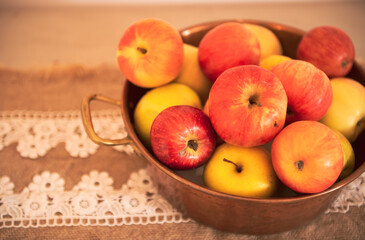 Some fresh eco read apples on a cooper basket placed on a wooden table. Decor with bio food products.