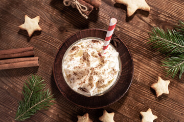 Xmas flat lay composition on wooden backdrop with Christmas drink homemade eggnog in center.