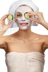 Beautiful girl with a mask and cucumber slices on his face on a white background