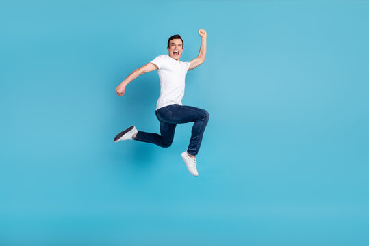Full size photo of young cheerful guy go run jump up hurry fast isolated over blue color background
