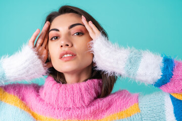 Close portrait of a young woman in a sweater on a blue background with graceful hands, long thin fingers, two cute silver rings, plump nude lips