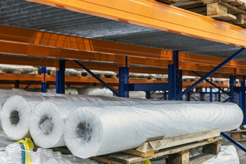 rolls of cellophane lie on the shelves of a large warehouse