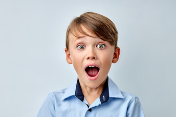 caucasian little boy amazed by news with opened mouth isolated gray color background. Cute young...
