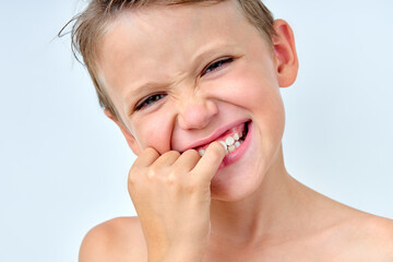 child boy touching teeth, checking the cleanliness, looking at mirror. isolated on white studio background, portrait. shirtless caucasian kid having perfect teeth, smile, looks squinting