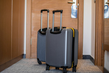 gray suitcases at the entrance of the hotel room's orange door, 