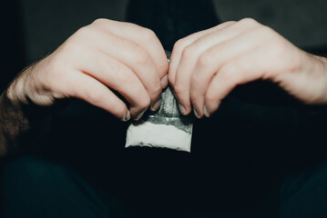 Obraz premium Criminal holding plastic bag with drug.Man holding transparent plastic zip lock bag with drugs. Concept-criminal with drugs.closeup,selective focus,toned.