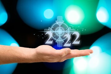 Businessman holding virtual 2022 number with bokeh background for merry Christmas and happy new year concept.
