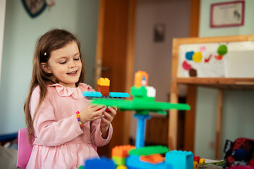 Adorable girl playing with toys at home. Little child playing with lots of toys indoor