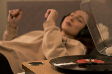 woman lying in bed smiling listening music with headphones and accompanying, happy woman listening to music with headphones while lying down