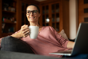 Woman working on laptop from home. Beautiful woman relaxing at home..