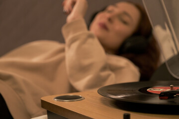 woman lying in bed smiling listening music with headphones and accompanying, happy woman listening to music with headphones while lying down
