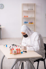 Young male chemist in drugs synthesis concept
