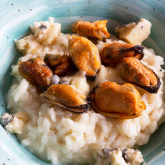 Close-up of seafood risotto in a blue plate, top view. Risotto with mussels and dor blue cheese. Haute cuisine in restonan. Delicious and healthy Mediterranean cuisine.