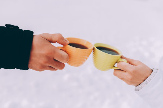 Two cups of coffee in the hands of happy couple. Winter theme