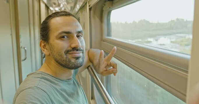 A young attractive man Takes a selfie on a train ride. Welcome hand sign.