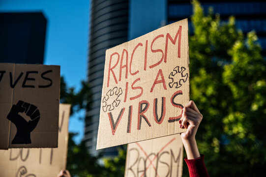 Activist showing signboard with Racism is a virus inscription during meeting