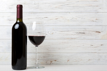 Glass of red wine and a bottle on colored table. Flat lay, top view wth copy space