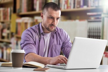 Reads an e-book in the university library. A man is studying at the institute. Surf the Internet