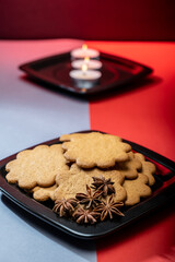 A pile of home made gingerbread cookies on a plate against festive background.