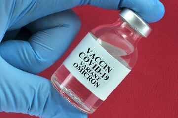 Concept de produit vaccinal contre le variant omicron dans un flacon tenue par une main gantée en...
