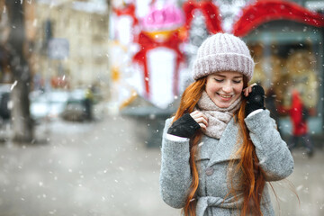 Merry ginger lady walking at the city with snowflakes