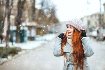 Emotional ginger lady walking at the city with snowflakes