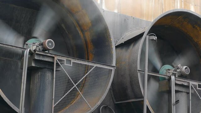Close-up of big industrial fans in a factory. Ventilation of plant building. Industrial air conditioning system on the wall outdoors. Steam from the indistrial plant in the air