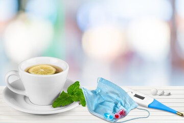 Flu season. Medical mask, pills, thermometer, and lemon tea.