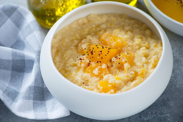 Close-up of pumpkin and millet porridge served in a white bowl, selective focus, horizontal shot