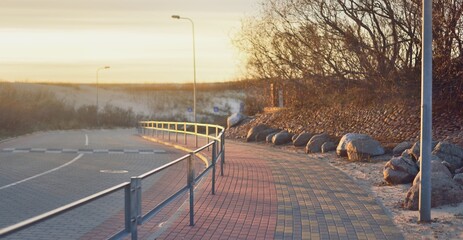 An empty bicycle road and pedestrian walkway (promenade) to the Baltic sea coast at sunset....