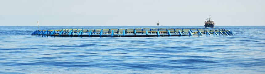 Fish farm in an open Mediterranean sea, fishing boat (small ship) close-up, Spain. Food industry,...