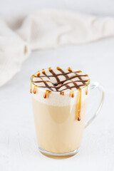 Caramel macchiato with creamed coconut in a glass mug.