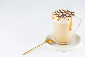 Vegan caramel macchiato with coconut cream in a glass mug.