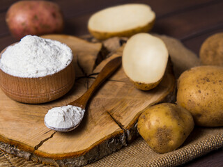Potato starch with potatoes on a dark wooden background.