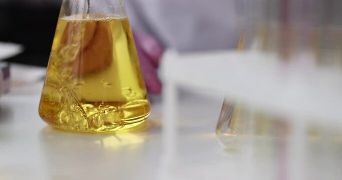 Liquid is added flask with yellow oily liquid carrying out chemical experiment