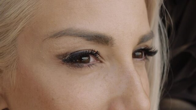 Blond young woman dressed as angel with black wings. Brown-eyed fashion female model. Extreme close-up.