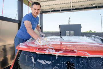 Manual car wash. A man with soapy water washes his car. Cleanliness concept